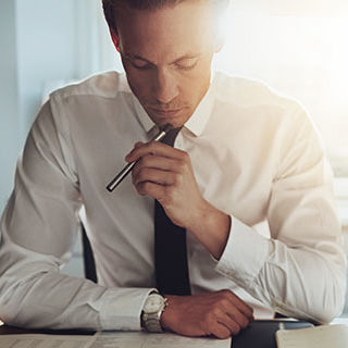 Male Accountant Holding a Pen and Thinking - Lead Image for CPA – Certified Public Accountant Page