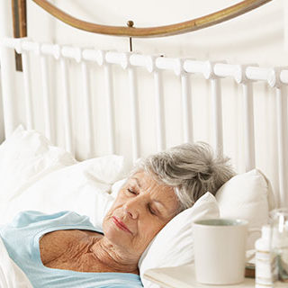 Doctor Staring at Sleeping Elderly Woman - Lead Image for Hospice Page